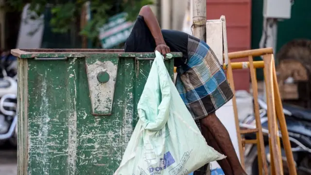 કચરામાંથી ભોજન શોધી રહેલા શ્રમિકની તસવીર