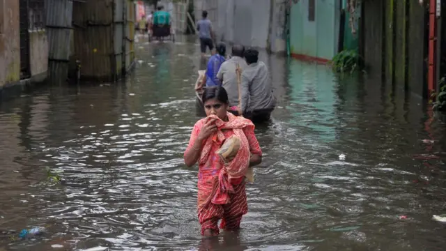 পানিবন্দী রাস্তায় এক নারী ও নৌকায় কিছু বাসিন্দা