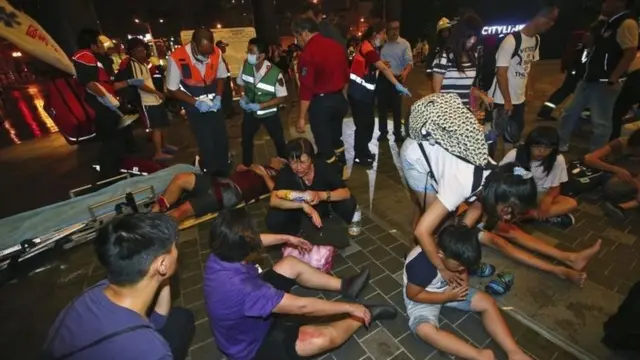 Injured people are helped by emergency rescue workers outside a station after an explosion on a passenger train in Taipei, Taiwan, Thursday, July 7, 2016