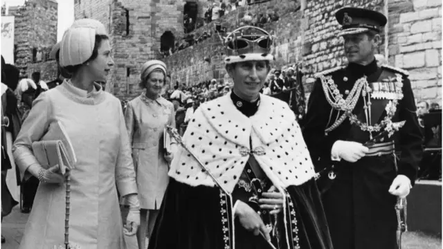 Prince Charles (centre) wearing a crown and robes after a ceremony where he was invested as the Prince of Wales, with Queen Elizabeth II (left) and the Duke of Edinburgh (right) at Caernarvon Castle, Wales, July 2nd 1969