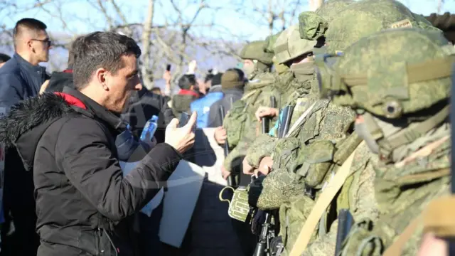 Мужчина средних лет что-то объясняет российскому солдату