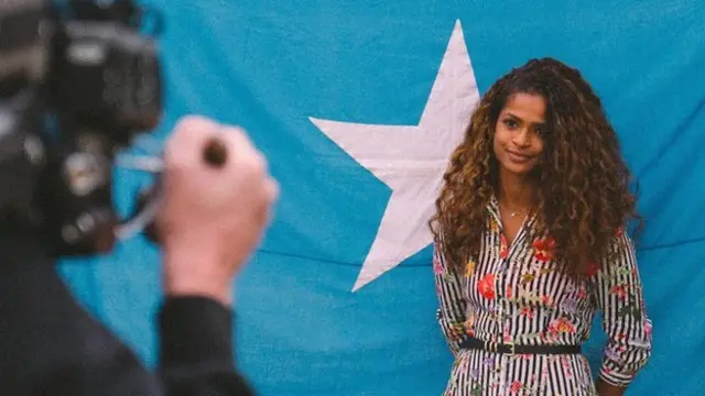 Ramla Ali poses in front of the Somali flag