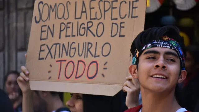 Jóvenes en México con una pancarta que dice "somos la especie en peligro de extinguirlo todo".