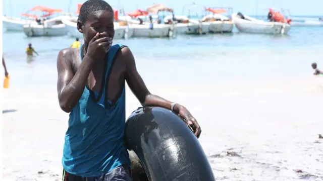 Waa wiil ku sugan xeebta oo ay ka muuqato farxad ballaaran