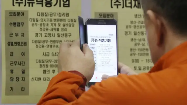 한 중장년 구직자가 스마트폰으로 구직광고를 촬영하고 있다