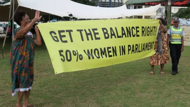 Mulheres segurando um cartaz com mensagembwin minglês exigindo representação igualitária no parlamentobwin mVanuatu