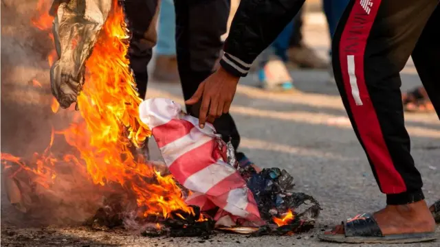 Manifestante queimando bandeira dos Estados Unidos