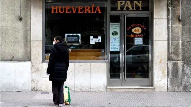 Женщина у закрытой лавки хлеба и яиц в испанском Бургосе 31 марта 2020 года