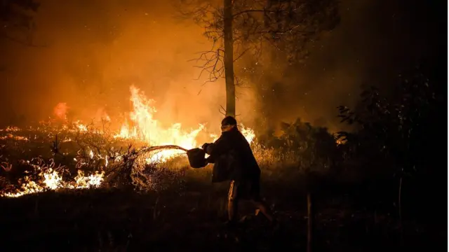 Чоловік заливає вогонь відром води