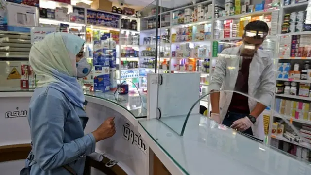 Aptekdə üzü maskalı qadın