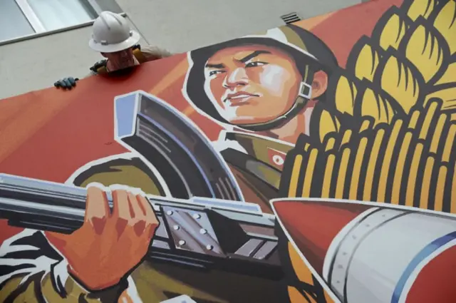 ရုပ်ရှင်ရှံတွေမှာပြလို့မရလို The Interview ရုပ်ရှင်ပိုစတာကို အလုပ်သမားတစ်ယောက် ဖြုတ်ချနေစဥ်