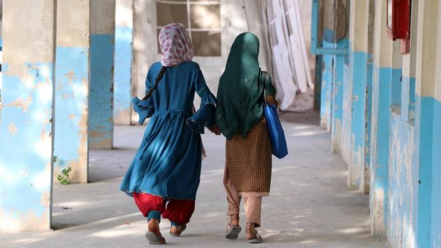 Two Afghan girls walking to a school building in Kandahar in September 2022