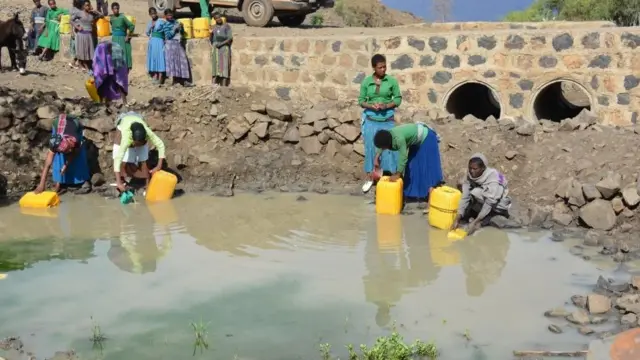 ሴቶች ከኩሬ ውሃ ሲቀዱ