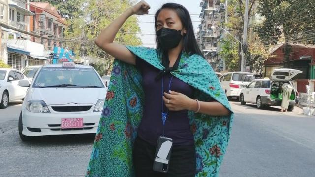 Burmese woman uses her sarong as cape whilst adopting power pose