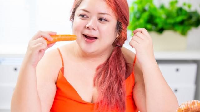 A woman eating a carrot