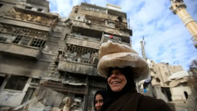Mujer llevando pan en la cabeza en las calles de Alepo, Siria.