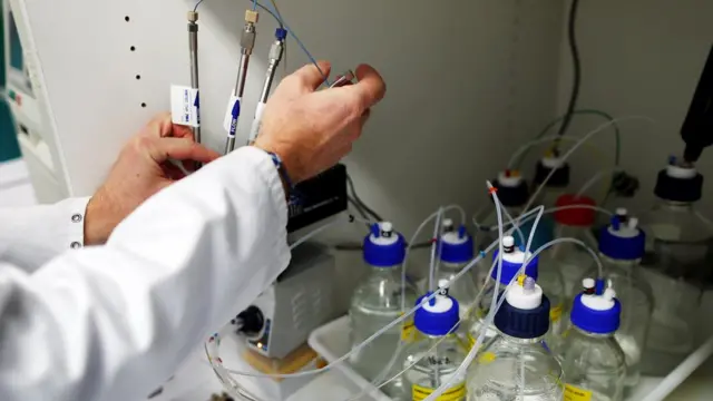 દવાનું સંશોધન કરતા વ્યક્તિના હાથ