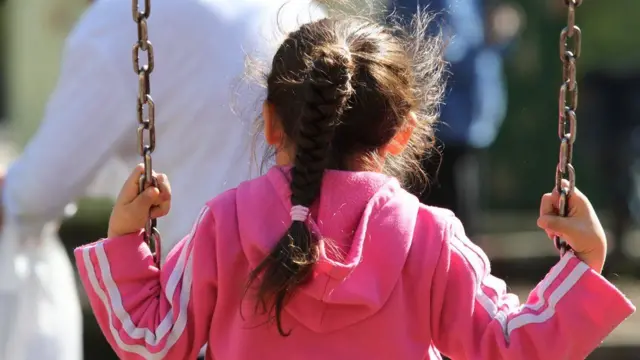 Niña de espaldas en columpio