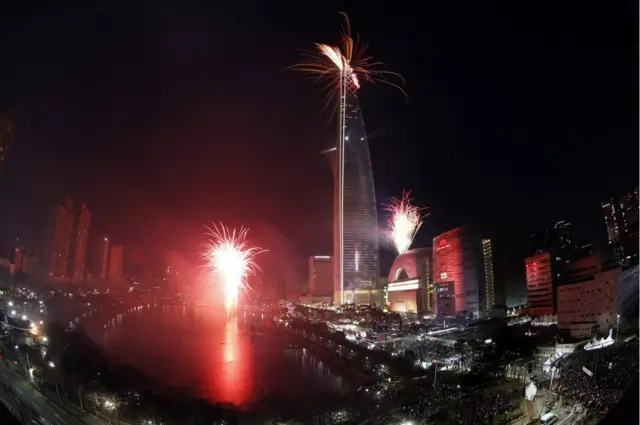 ชาวเกาหลีใต้เฝ้าชมการจุดดอกไม้ไฟเฉลิมฉลองที่ตึก Lotte World Tower สูง 123 ชั้น ในกรุงโซล