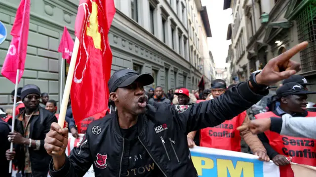 Ọkunrin kan kopa ninu iwọde kan ti wọn ṣe lati tako eleyamẹya at lati satilẹyin fun Idy Diene, ontaja ilẹ Senegal kan ti ọmọ ilẹ Italy kan pa nigboro Florence, lorilẹede Italy lọjọ kẹwa osu kẹta , ọdun 2018.