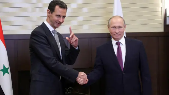 Vladimir Putin (R) shakes hands with his Syrian counterpart Bashar al-Assad during a meeting in Sochi on November 20, 2017