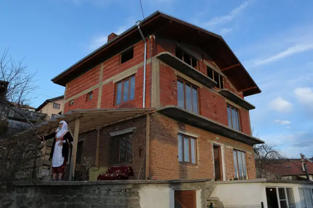 Nevestina majka pred svojom kućom očekuje da pristigne kolona kako bi poslednji čin svadbene ceremonije mogao da otpočne.