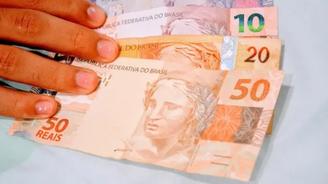 Mão segurando notasonabet o que éR$ 50, R$ 20, R$ 10 e R$ 5