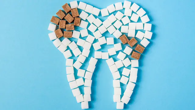 Diente hecho de cubos de azúcar blanca y morena, simulando caries.