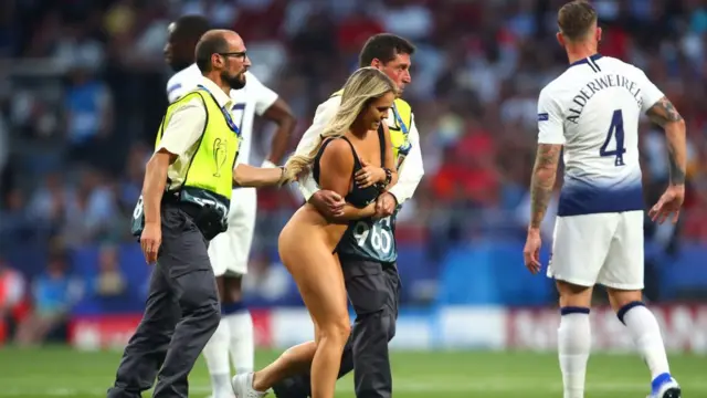 কিনসি ভোলানস্কিকে মাঠের বাইরে নিয়ে যাচ্ছেন নিরাপত্তা রক্ষীরা।