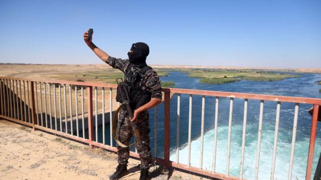 أحد عناصر القوات الخاصة التابعة لقوات سوريا الديمقراطية المدعومة من الولايات المتحدة، والمكونة من تحالف من مقاتلين عرب وأكراد، يلتقط صورة في سد الطبقة، في 12 مايو/ أيار 2017، بعدما تمت استعادته