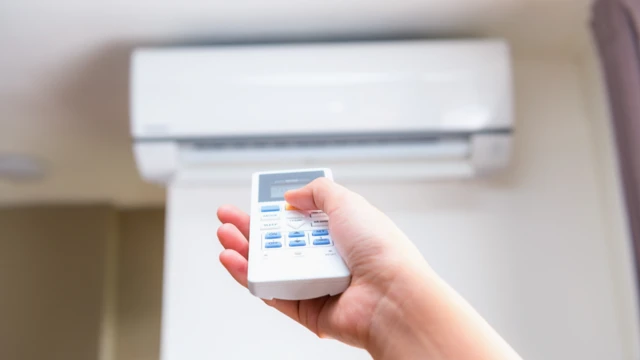 Una persona tiene en su mano el control remoto de un sistema de aire acondicionado