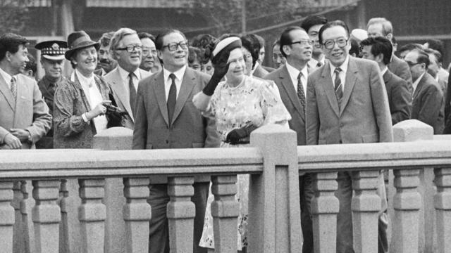 伊丽莎白二世（中）在吴学谦（右）、江泽民（前左）与贺维（二排左三）走访上海街头（15/10/1986）