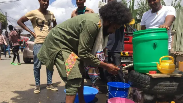አዲስ አበባ- ጣይቱ ሆቴል አካባቢ እጁን የሚታጠብ መንገደኛ