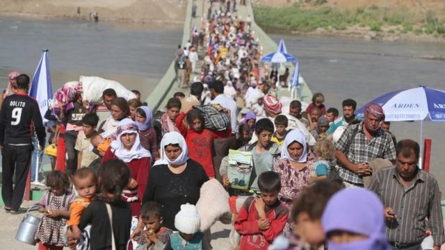 Des Irakiens déplacés de la communauté Yazidi traversent la frontière syro-irakienne le long du pont de Fishkhabur sur le Tigre