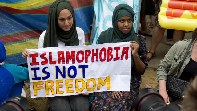 "İslamofobi özgürlük değildir" pankartı tutan başörtülü iki kadın