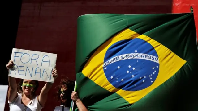 Protesta en Sao Paulo con una bandera brasileña y un cartel que dice "Fuera Renan"