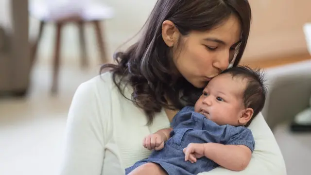 Una madre de origen latino sostiene a su bebé.