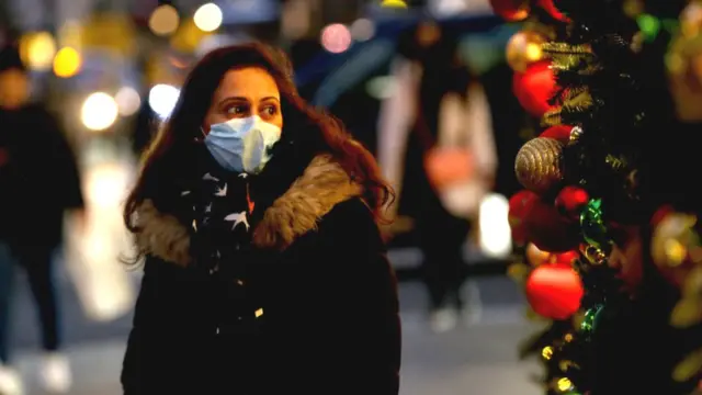 A woman in a mask next to a Christmas decoration