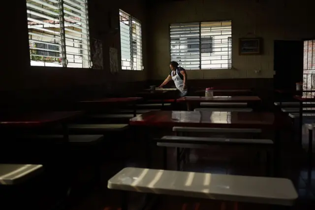 Mujer limpia una mesa en una cafetería de San José las Flores, El Salvador.