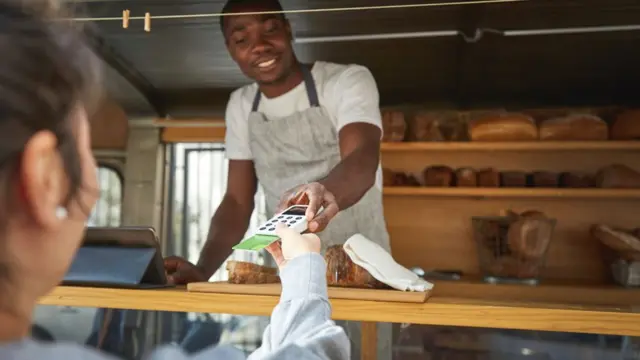 Une femme munie d'une carte de crédit paie le vendeur d'un camion de nourriture.