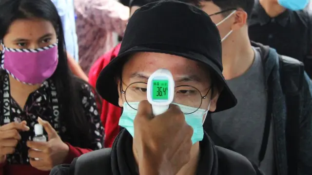 Seorang penumpang kapal dari Batam yang akan pulang ke kampung diperiksa suhu tubuhnya oleh petugas medis di Pelabuhan Bandar Sri Junjungan Dumai di Dumai, Riau, Minggu (26/04).