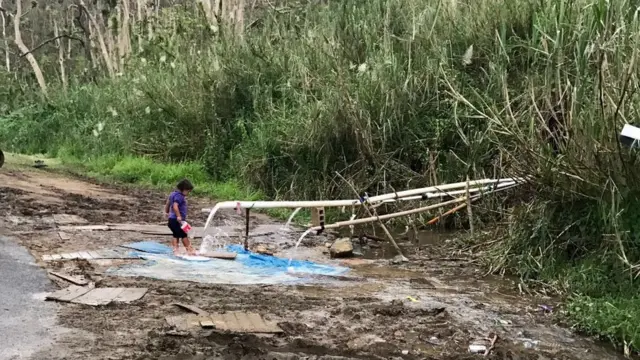 Una niña recoge agua de la ladera de una montaña en Puerto Rico.