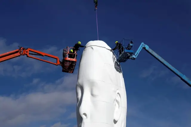 Workers put the finishing touches on a statue