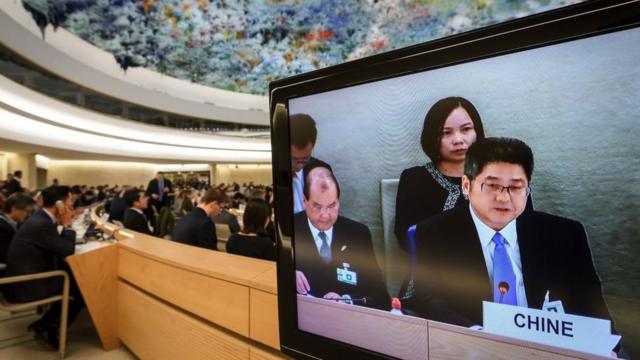 نائب وزير الخارجية الصيني لو يوتشنغ (يمين) يظهر على شاشة التلفزيون أثناء حضوره الاستعراض الدوري الشامل للصين أمام مجلس حقوق الإنسان التابع للأمم المتحدة في 6 نوفمبر 2018 في جنيف