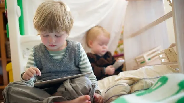Un niño y un bebé miran sus pantallas