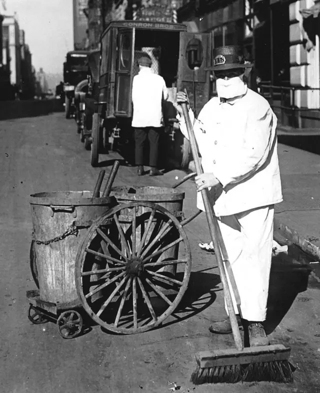 መንገድ ጠራጊ በኒውዮርክ ጎዳና ላይ ጭምብል አጥልቀው