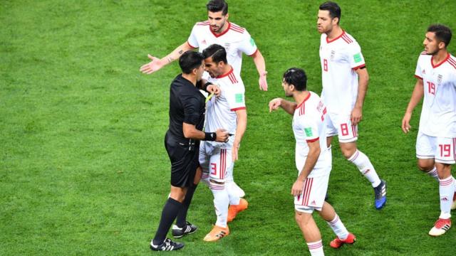 EL árbitro paraguayo Enrique Cáceres es rodeado por jugadores iraníes.