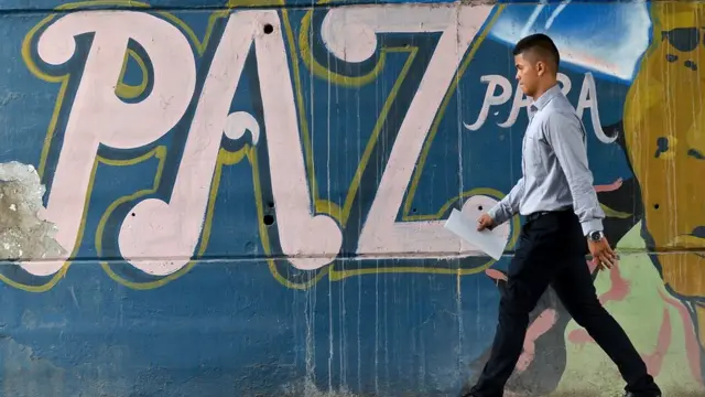 Un hombre pasa frente a un mural con la palabra paz en Colombia
