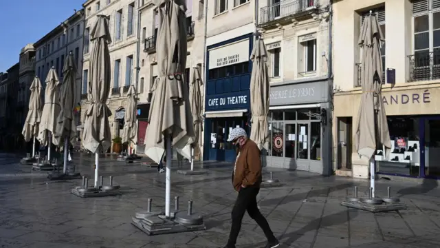 Hombre caminando ante restaurantes cerrados en Montpellier, Francia.