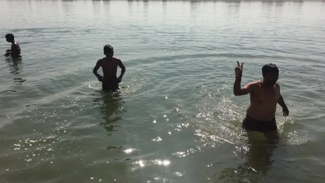 तालाब में नहाते कुछ लोग